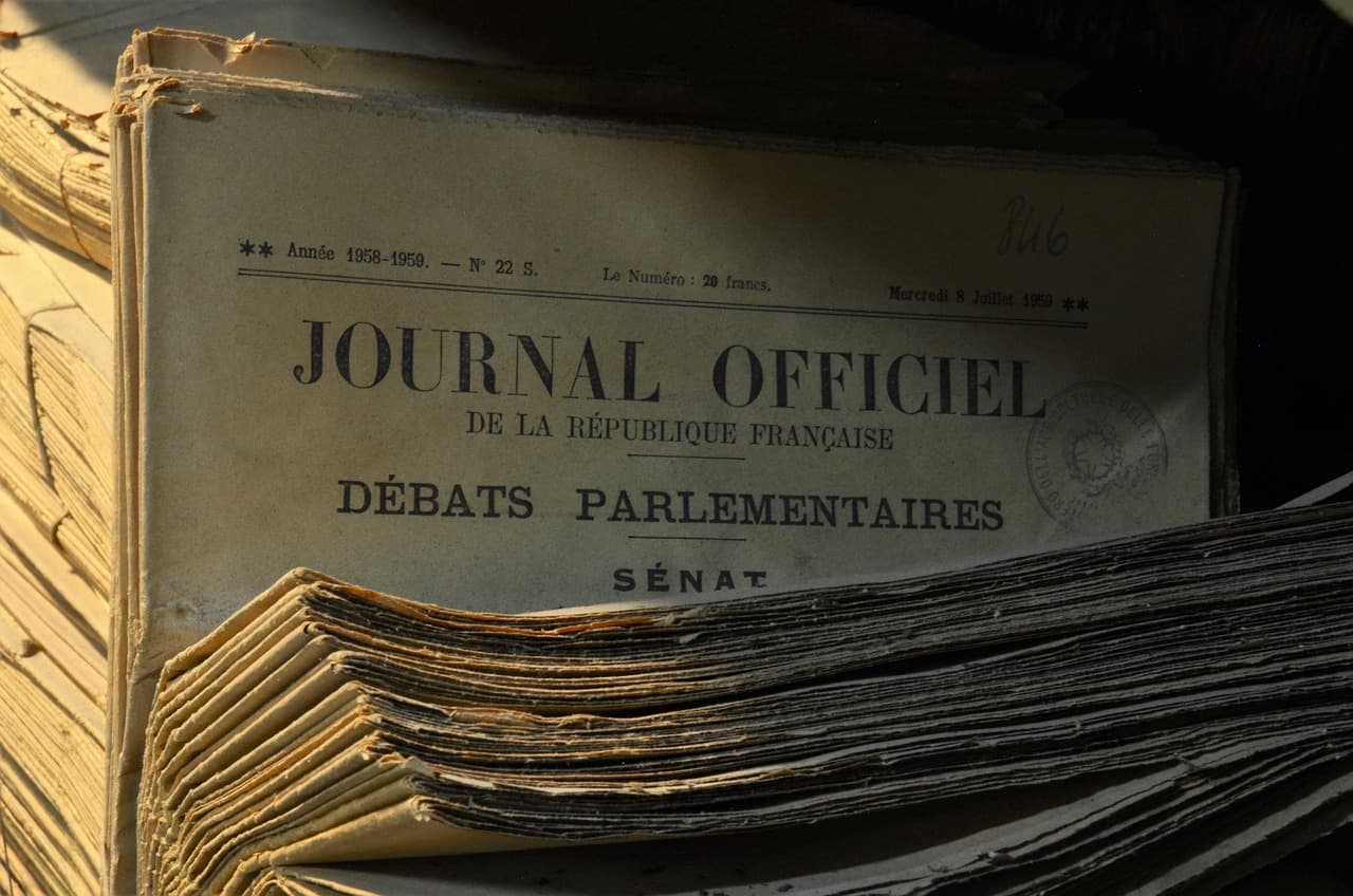 Rows of old legal documents and bound records filling the shelves of a historic parliamentary archive