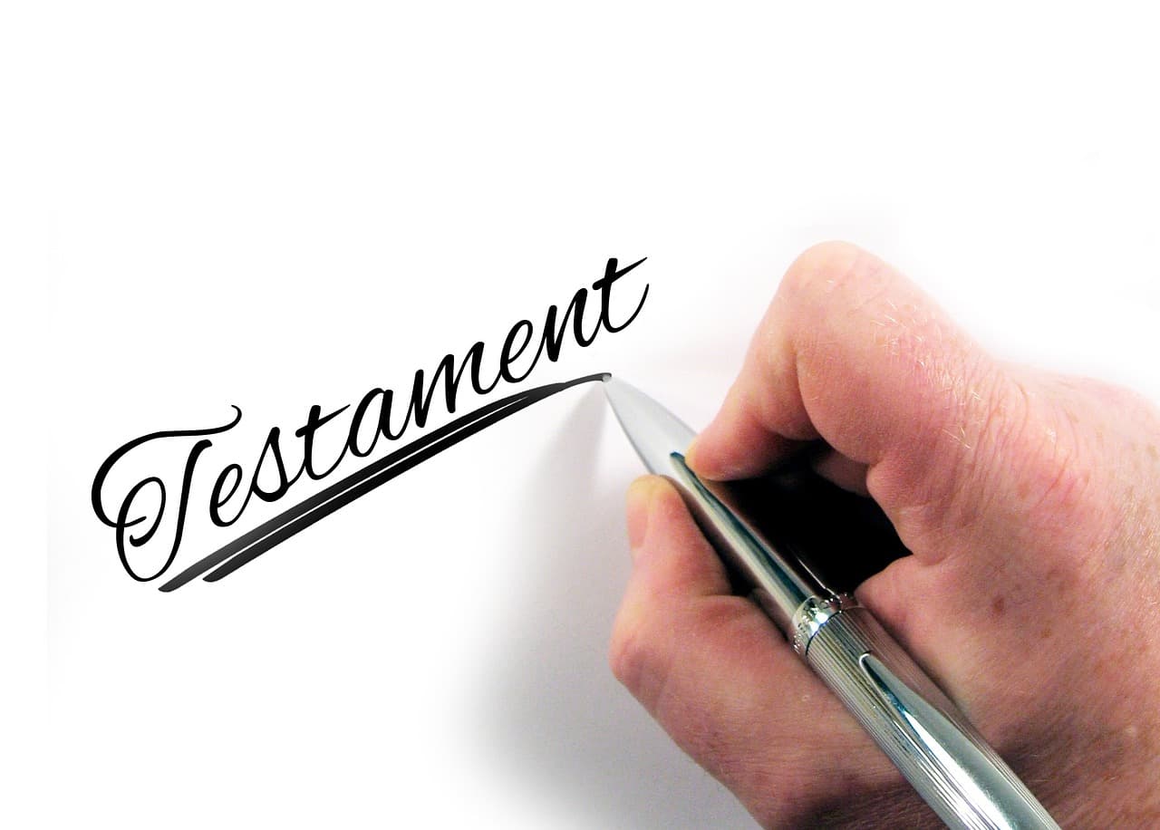 A hand writing out a testament document on paper with a ballpoint pen